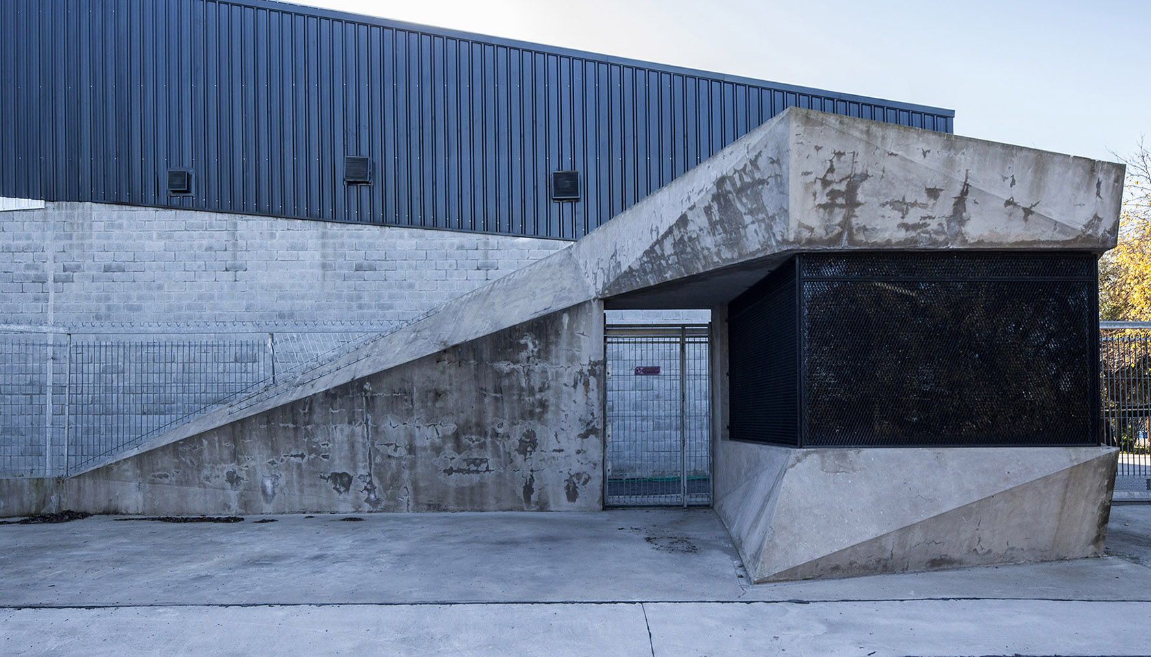 Foto detalle de ingreso peatonal, plegado de hormigón, arquitectura industrial contemporánea, plegado en acero